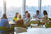 Empresarios almorzando y socializando en cafetería de rascacielos - foto de stock