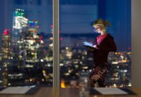 Empresaria con tableta digital trabajando hasta tarde en la oficina de rascacielos - foto de stock