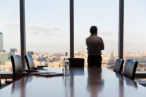 Nachdenklicher Geschäftsmann schaut aus dem Fenster eines städtischen Konferenzraums — Stockfoto