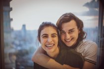 Portrait happy young couple hugging at window — Stock Photo