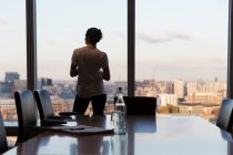 Nachdenkliche Geschäftsfrau blickt aus dem Bürofenster eines Hochhauses — Stockfoto