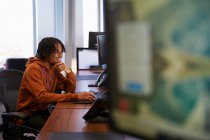 Jovem empresário sorrindo trabalhando no computador no escritório — Fotografia de Stock