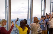 Geschäftsleute machen Selfies am Bürofenster eines Hochhauses — Stockfoto