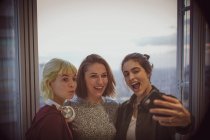 Empresárias felizes tirando selfie na janela do escritório — Fotografia de Stock