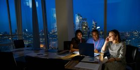 Uomini d'affari che lavorano fino a tardi al laptop nella sala conferenze dei grattacieli — Foto stock