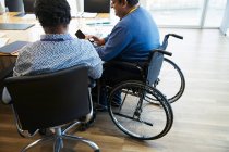 Geschäftsmann im Rollstuhl nutzt Smartphone bei Besprechung im Konferenzraum — Stockfoto