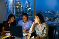 Business people working late at laptop in urban highrise office — Stock Photo