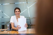 Portrait confident smiling businesswoman with paperwork in meeting — Stock Photo