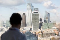 Бизнесмен смотрит на солнечный городской пейзаж Лондона из окна офиса, Великобритания — стоковое фото