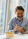 Empresário sorrindo usando telefone inteligente no almoço — Fotografia de Stock