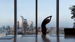Businesswoman stretching at highrise office window, London, UK — Stock Photo