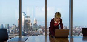 Зайнята жінка користується ноутбуком у високогірному офісі, Лондон, Велика Британія. — стокове фото