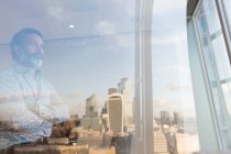 Pensativo hombre de negocios mirando por la ventana de la oficina de rascacielos, Londres, Reino Unido - foto de stock