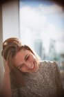 Счастливая деловая женщина смеется с рукой в волосах у окна — стоковое фото