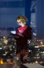 Giovane donna d'affari con tablet digitale che lavora fino a tardi alla finestra dell'ufficio — Foto stock