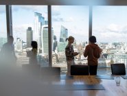 Деловые люди разговаривают у окна высотного офиса, Лондон, Великобритания — стоковое фото