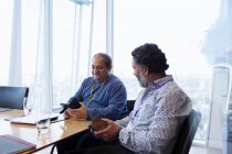 Empresários usando telefones inteligentes em reunião de sala de conferências — Fotografia de Stock