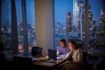 Les gens d'affaires travaillant tard à l'ordinateur portable dans un bureau de grande hauteur, Londres, Royaume-Uni — Photo de stock