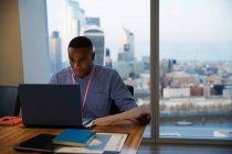 Зосереджений бізнесмен працює на ноутбуці у високогірному офісі (Лондон, Велика Британія). — стокове фото