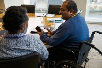 Empresário em cadeira de rodas conversando com colega em reunião — Fotografia de Stock