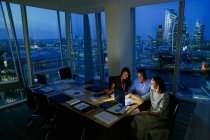 Gente de negocios que trabaja hasta tarde en Highrise Office, Londres, Reino Unido - foto de stock