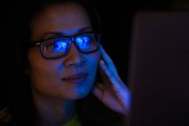 Close up laptop reflection in eyeglasses of businesswoman working late — Stock Photo