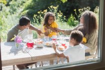 Счастливая семья обедает на солнечном летнем дворике — стоковое фото