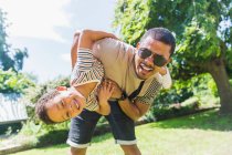 Retrato brincalhão pai e filho no quintal ensolarado — Fotografia de Stock