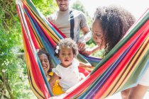 Portrait cute toddler girl in sunny summer hammock with family — Stock Photo