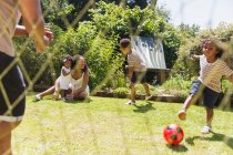 Happy family playing soccer in sunny summer backyard — Stock Photo