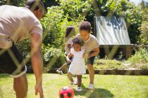 Família jogando futebol no ensolarado quintal de verão — Fotografia de Stock