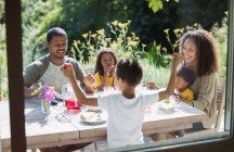 Glückliche Familie genießt das Mittagessen im Garten auf der sonnigen Sommerterrasse — Stockfoto