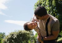 Pai brincalhão segurando filho feliz no quintal ensolarado verão — Fotografia de Stock