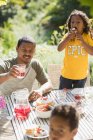 Батько і діти насолоджуються садовим обідом на сонячному літньому патіо — стокове фото