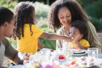 Family eating lunch at sunny summer patio table — Stock Photo
