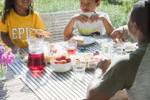 Almuerzo familiar en la soleada mesa del patio de verano - foto de stock