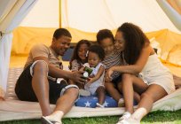 Famille heureuse utilisant un téléphone intelligent à l'intérieur de la tente — Photo de stock
