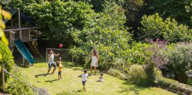 Famiglia che gioca a calcio nel soleggiato cortile estivo — Foto stock
