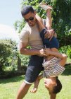 Playful father holding son upside down in sunny summer backyard — Stock Photo