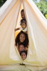 Porträt einer verspielten Familie, die aus dem Inneren des Zeltes blickt — Stockfoto