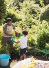Jardinage père et fils dans un jardin d'été ensoleillé — Photo de stock