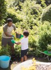 Padre e hijo de jardinería en el soleado jardín de verano - foto de stock