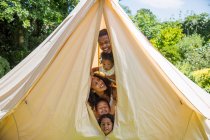 Portrait playful family peering from inside tent — Stock Photo