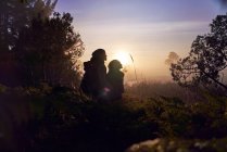 Silhueta jovem casal sereno desfrutando de caminhada na natureza ao pôr do sol — Fotografia de Stock