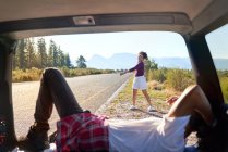 Feliz casal despreocupado relaxando fora do carro na ensolarada beira da estrada remota — Fotografia de Stock