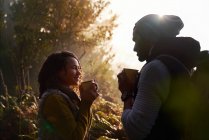 Щаслива молода пішохідна пара п'є каву в сонячному лісі — стокове фото