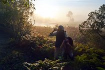 Любопытная молодая пара, путешествующая с биноклем и камерой в солнечных лесах — стоковое фото