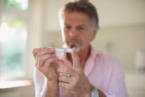 Hombre mayor con diabetes usando glucómetro en el dedo - foto de stock