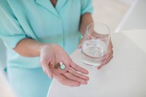 Donna anziana che prende vitamine con acqua — Foto stock