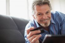 Portrait smiling senior man with headphones and credit card — Stock Photo